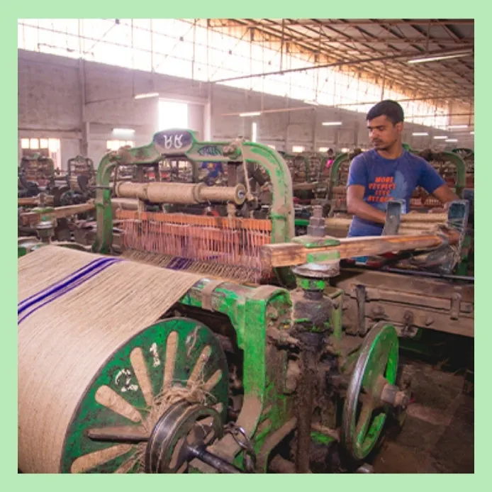Worker operating jute fabric weaving machine in a textile mill