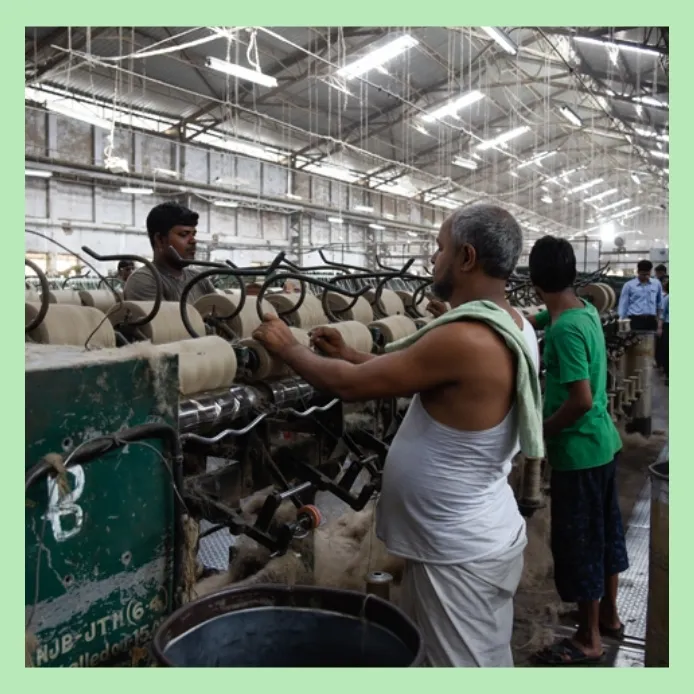 Workers operating spinning machines inside a jute yarn production factory in Bangladesh"